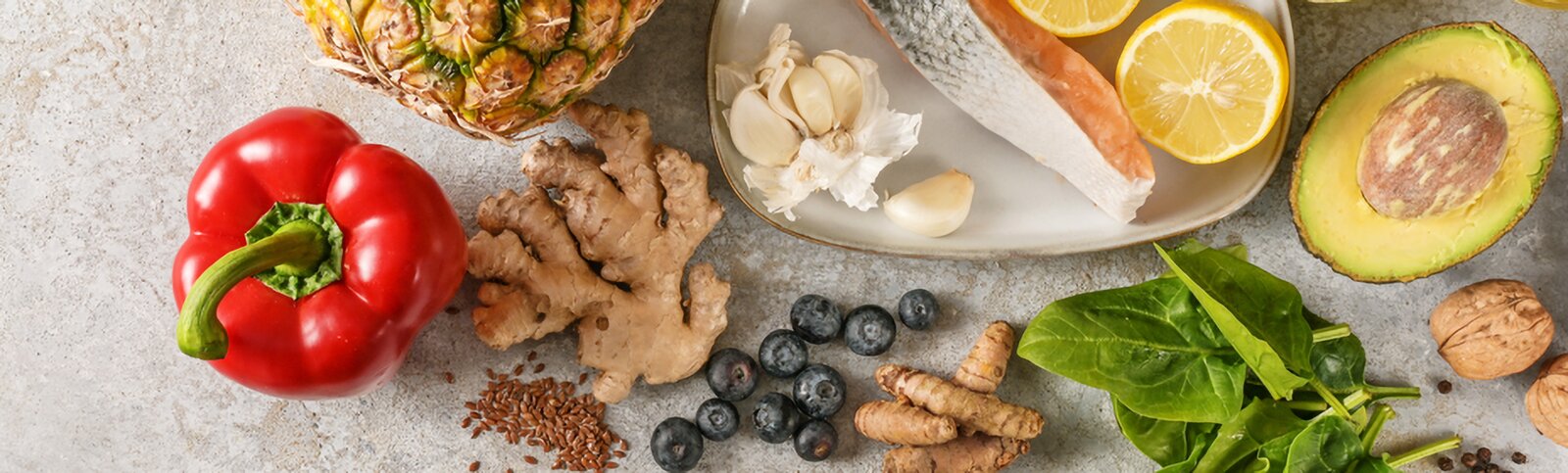 Flatlay mit entzündungshemmenden Lebensmitteln: Lachs, Beeren, Brokkoli, Walnüsse, Olivenöl und Kurkuma